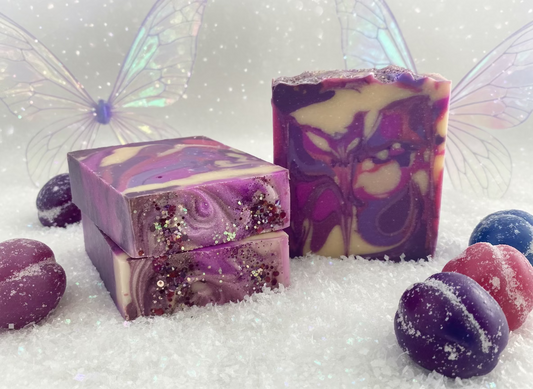 Two purple and white swirled soap bars with glitter on a dark surface.